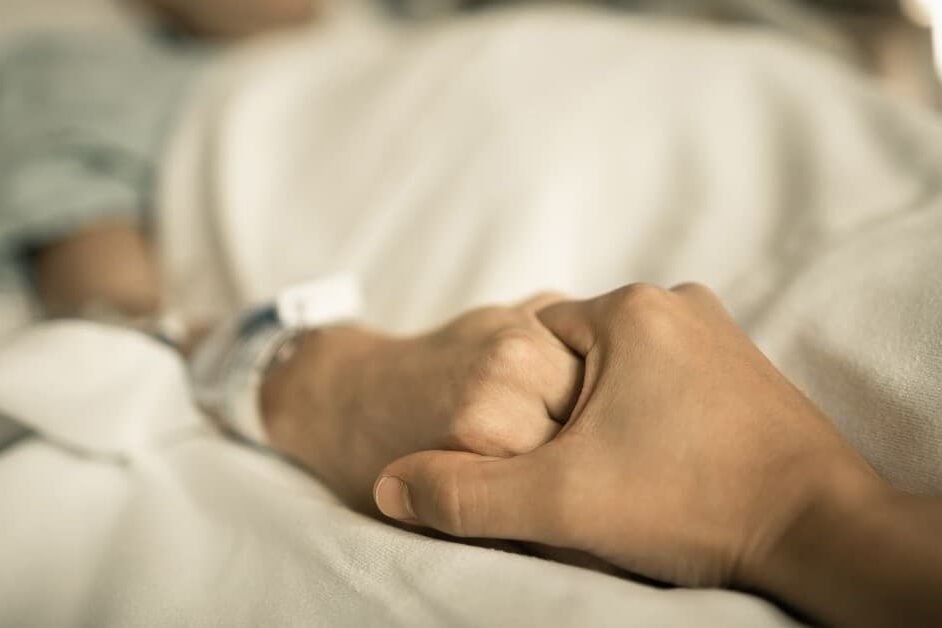 holding hands in hospital bed
